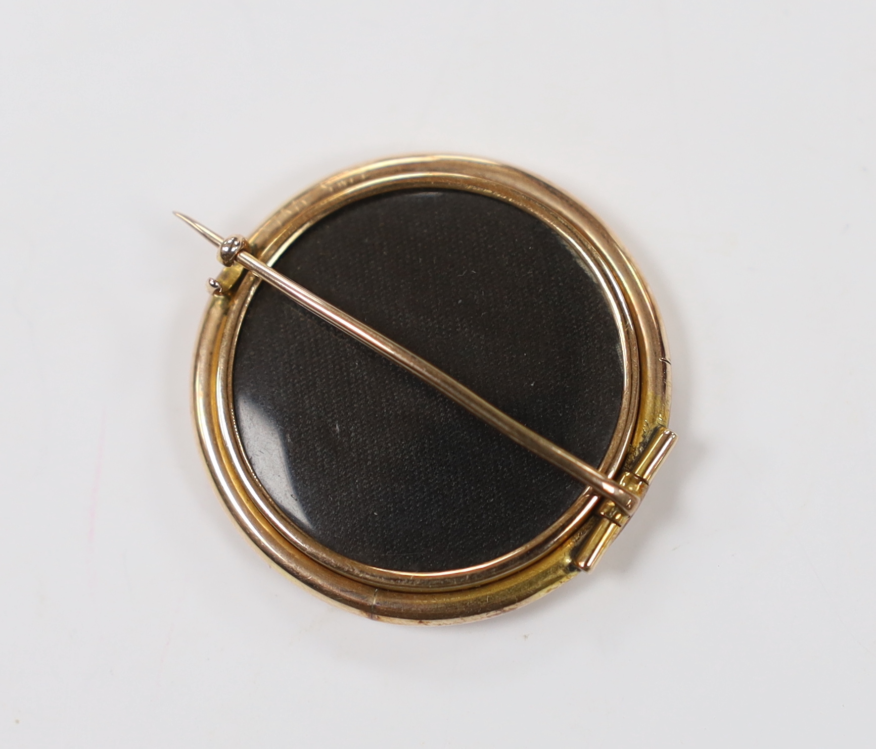 A 19th century yellow metal mounted circular brooch, with glazed back and inset miniature watercolour on ivory, depicting a lady in woodland scene, 31mm. CITES Submission reference, E5G6FZPZ